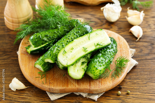 Freshly-salted cucumbers on a board with garlic and herbs