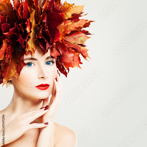 Autumn Lady. Beautiful Woman with Healthy Skin touching her Hand her Face. Makeup  Manicure and Fall Leaves Wreath