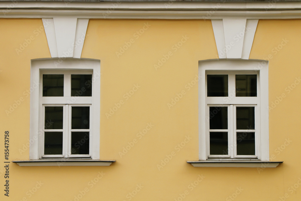 The facade of two windows of a yellow building.