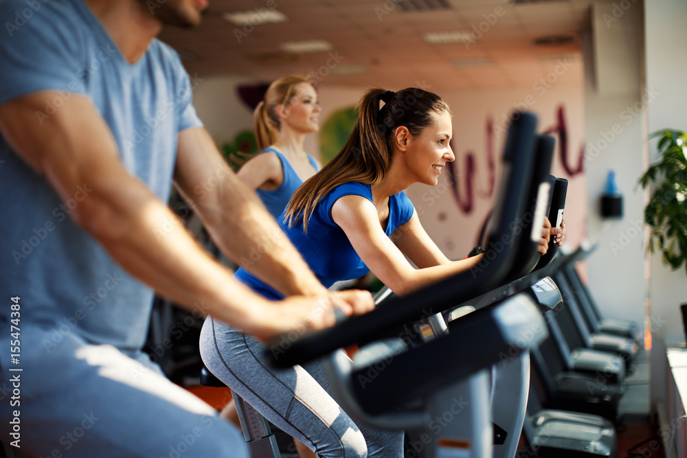 Young woman and man warming up on bikes in the gym