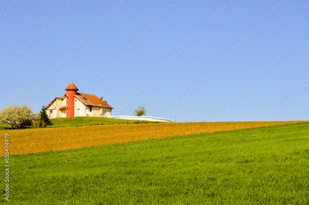 House with a turret over fields cultivated