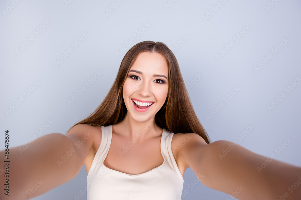 premium console Stand up instead Selfie mania! Cute young girl with a beaming smile is taking a shot on the  camera. She is so excited and amazed, wearing white casual singlet Stock  Photo | Adobe Stock