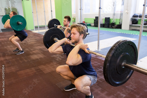 group of men training with barbells in gym