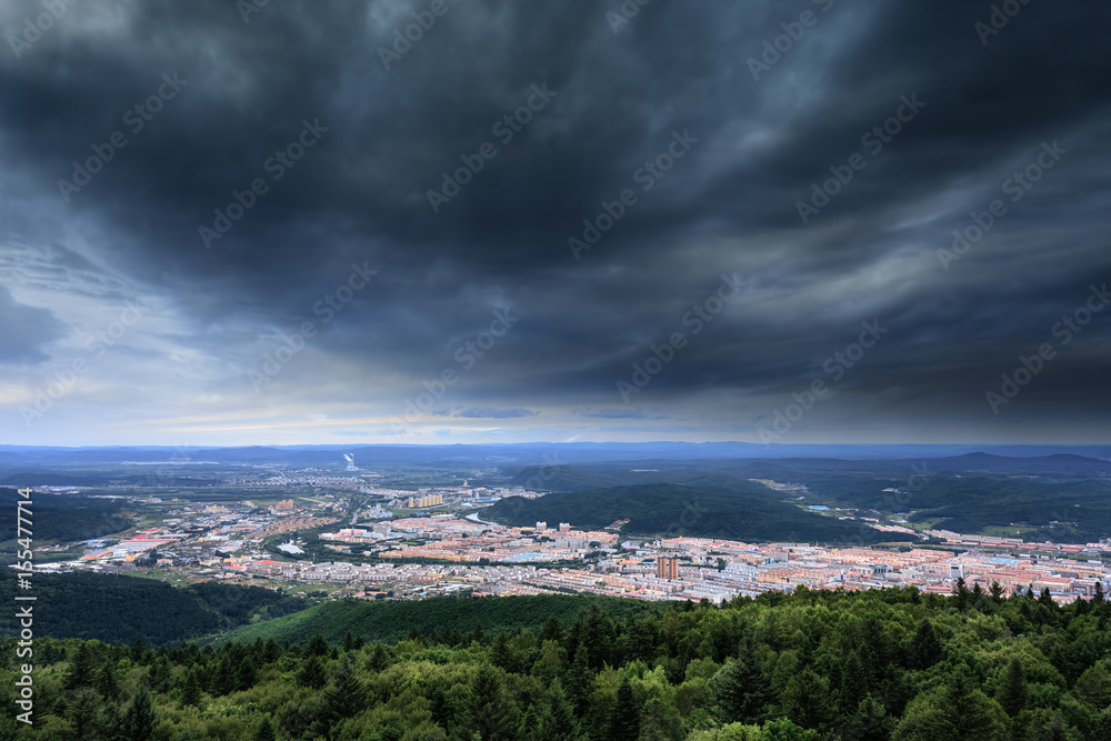 Aerial view of storm clouds over mountains and town.