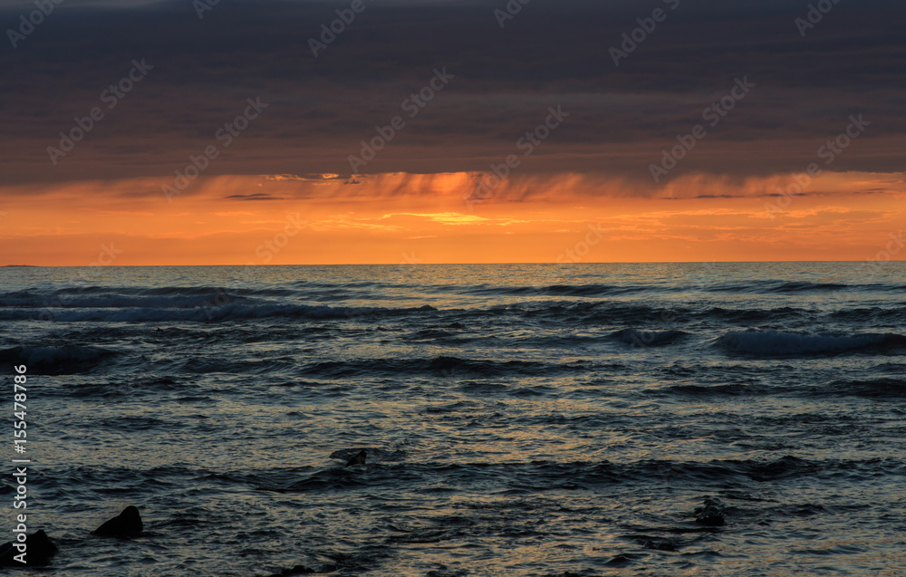 Sunset with rain clouds in the sea. Atmospheric phenomena concept