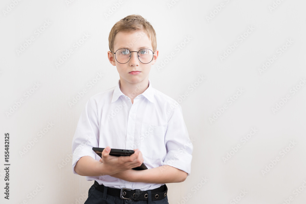 Attractive boy with a tablet with glasses and a white shirt. The concept of education, school, technology and fashion Attractive boy with a tablet with glasses and a white shirt. The concept of education, school, technology and fashion