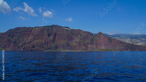 Madeira - Red cliffs and blue sky and ocean water from boat near Funchal