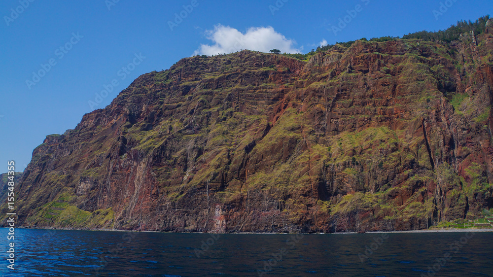 Madeira - Giant red cliffs and blue sky and ocean water and beach