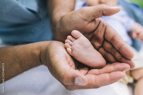.Father holding his son's little foot in an outdoor park. Lifestyle portrait