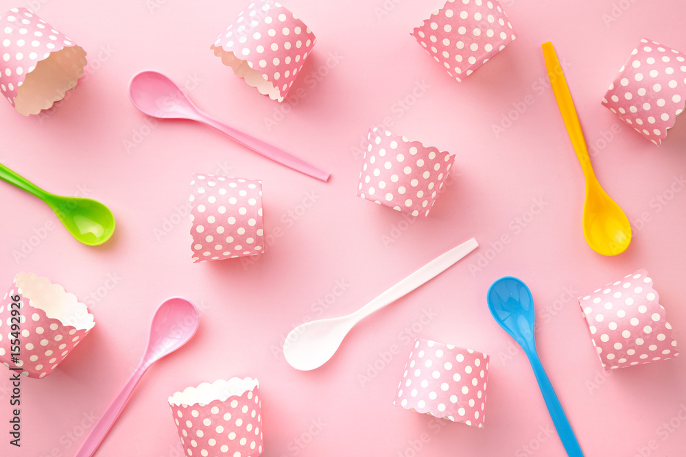 Colorful spoons and cupcake paper cups pattern on a pink background. Top view Colorful spoons and cupcake paper cups pattern on a pink background. Top view