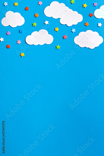 Stars and clouds in the sky. Paper elements on a blue background. Flat lay. Top view. Copy space.
