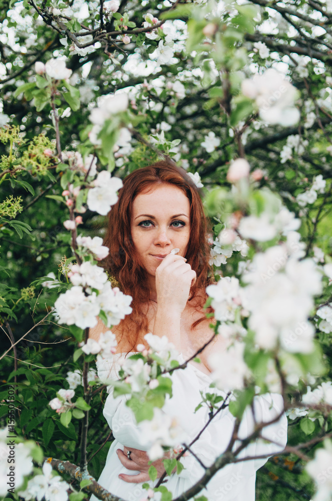 Red-haired girl with freckles near the apple tree Red-haired girl with freckles near the apple tree