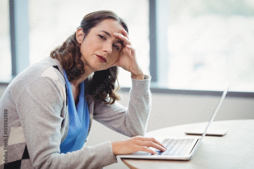 Obraz premium Portrait tired executive using laptop at desk