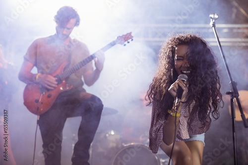 Cheeful female singer with male guitarist performing at nightclu photo