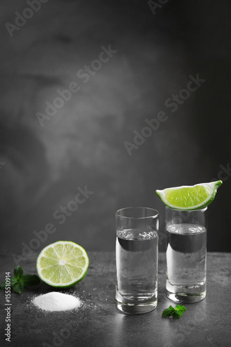 Tequila shots with juicy lime and salt on grey background