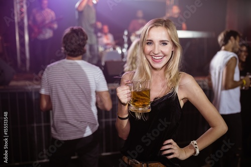 Portrait of smiling woman holding beer mug at nightclub