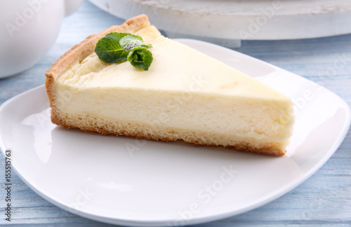 Plate with piece of tasty cheesecake on wooden table, closeup