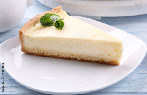 Plate with piece of tasty cheesecake on wooden table  closeup