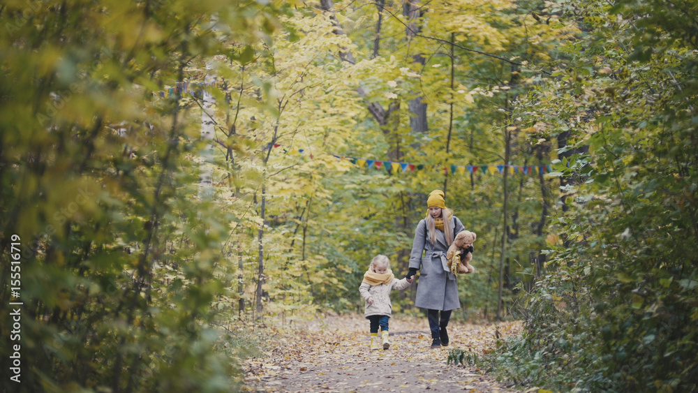 Fototapeta premium Mother and her daughter little girl walking in a autumn park
