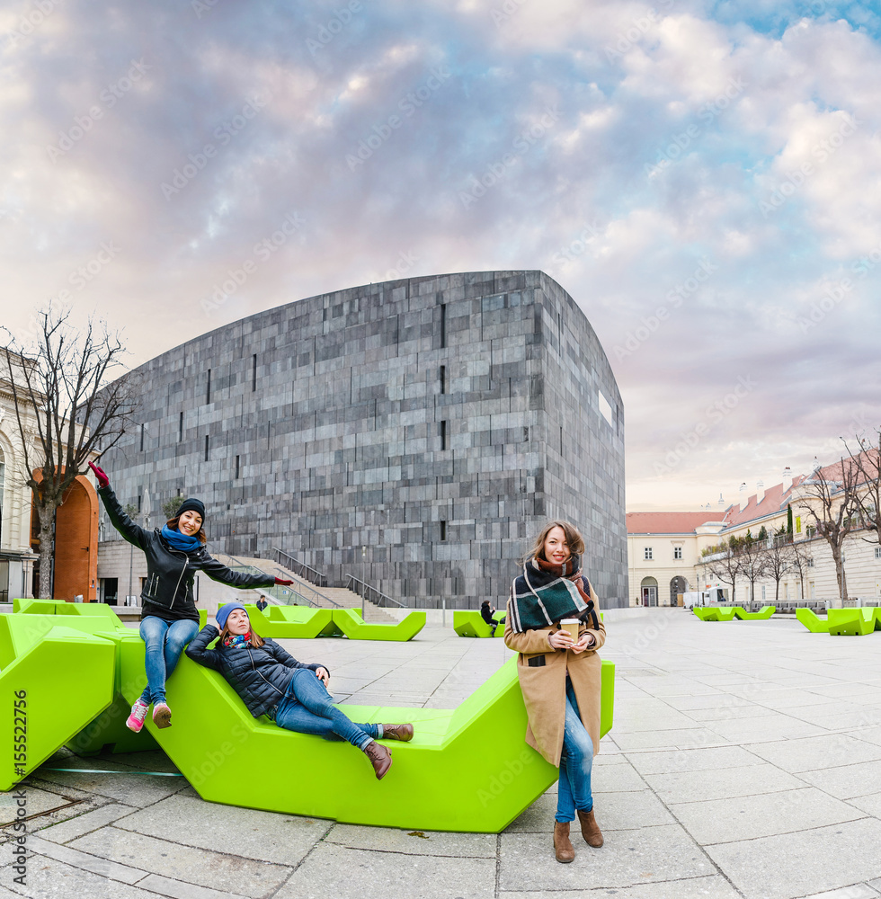 Fototapeta premium Group of friends having fun and sitting on the bench at park in Vienna