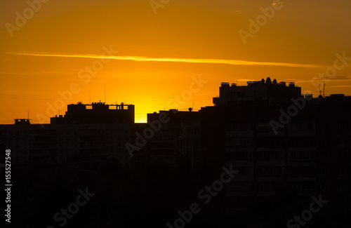 Yellow sunset over city, black silhouettes of buildings
