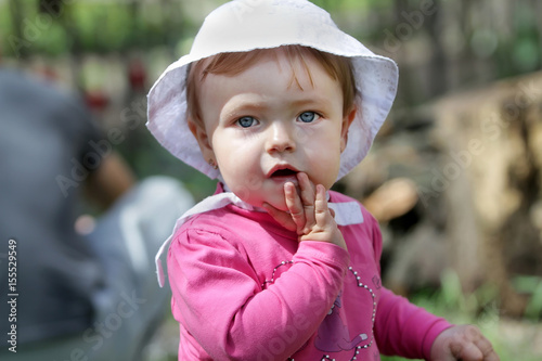 A charming girl in a pink dress covered her mouth with astonishment. A beautiful baby with big eyes opened her mouth in amazement.