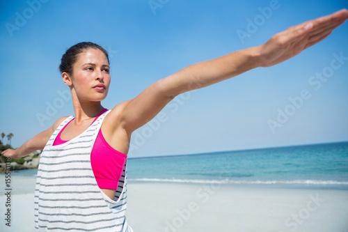 Young woman with arms outstretched exercising at beach