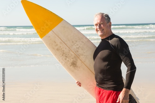 Photography Portrait of senior man with surfboard standing at beach