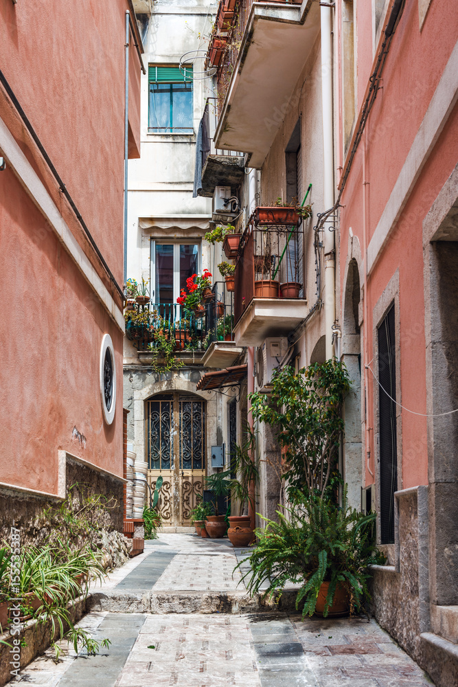 Narrow cobbled lane between red walls, Taormina
