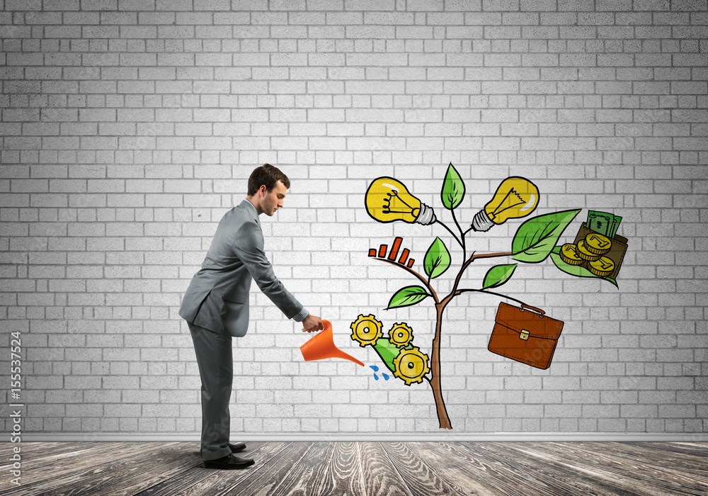 Young businessman in empty room watering drawn growth concept with can Young businessman in empty room watering drawn growth concept with can