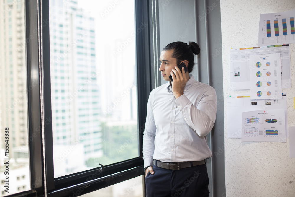 Businessman standing and using smartphone at workplace, 30-40 year old. Businessman standing and using smartphone at workplace, 30-40 year old.