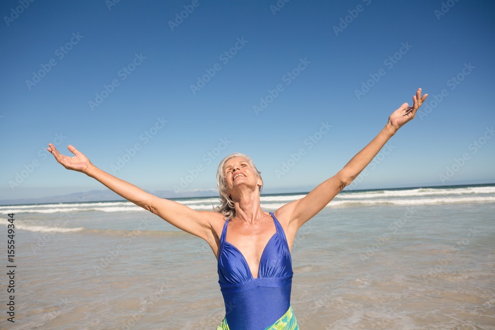 Senior woman with arms outstretched standing on shore Senior woman with arms outstretched standing on shore