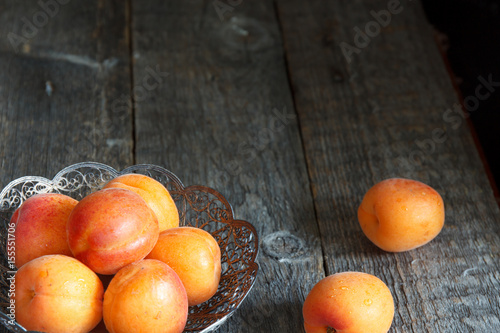 Apricots in a bowl on wooden background.