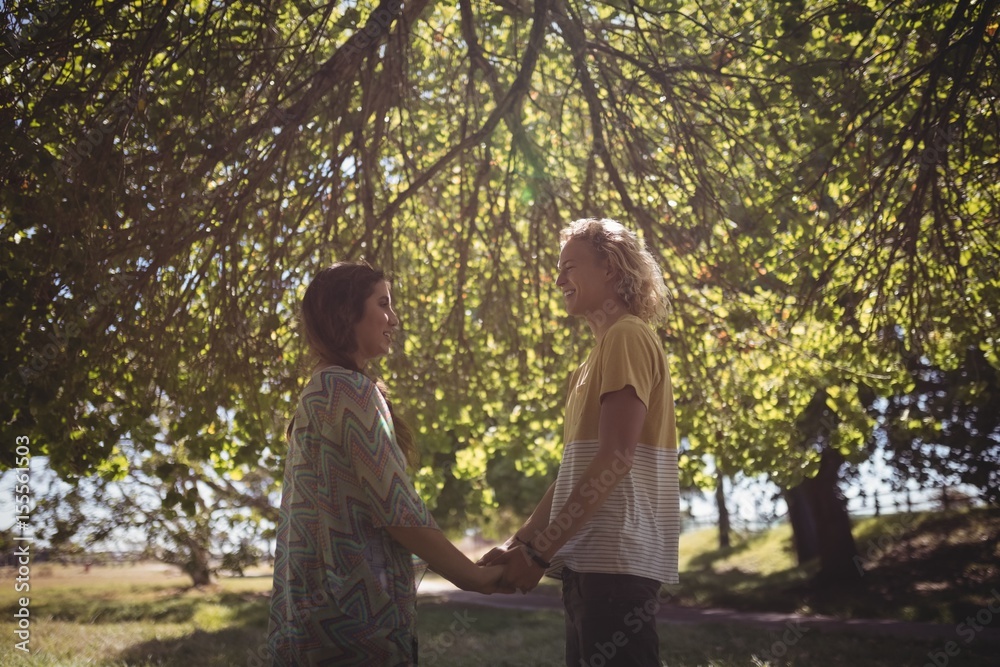 Side view of couple holding hands while standing on field Side view of couple holding hands while standing on field