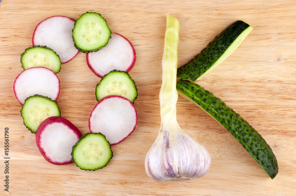 The word OK, made from circles of red radish, cucumbers and a head of garlic on a wooden background The word OK, made from circles of red radish, cucumbers and a head of garlic on a wooden background