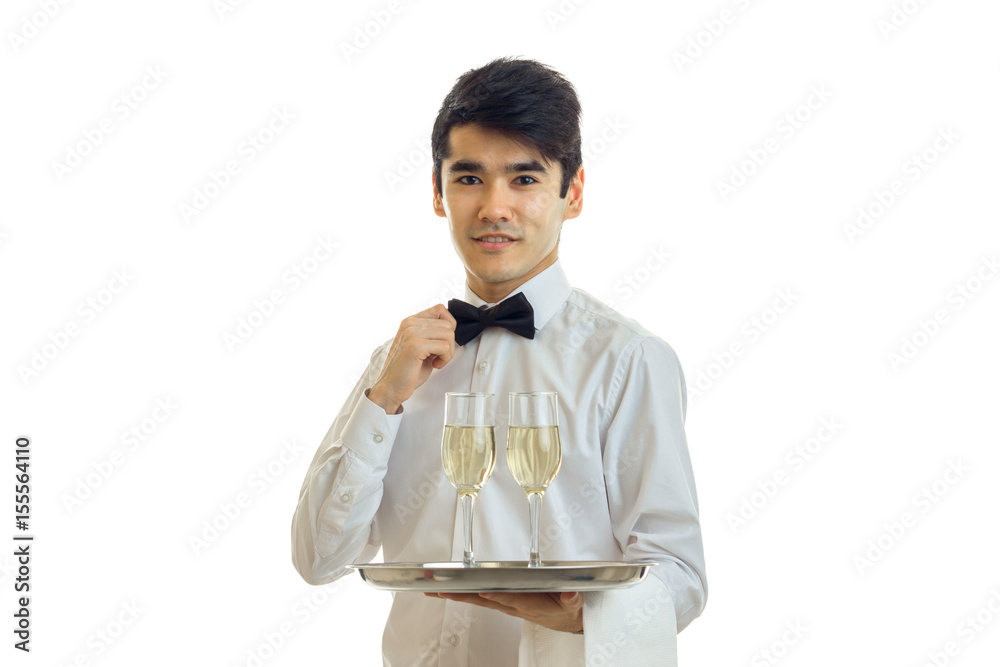 charming young waiter nicely dressed holding a tray with glasses and adjusts his bow tie hand charming young waiter nicely dressed holding a tray with glasses and adjusts his bow tie hand