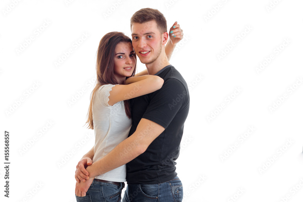 charming young guy is smiling looks right and hugging beautiful girl charming young guy is smiling looks right and hugging beautiful girl