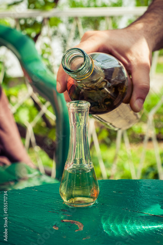 Pouring domestic brandy from bottle into glass photo