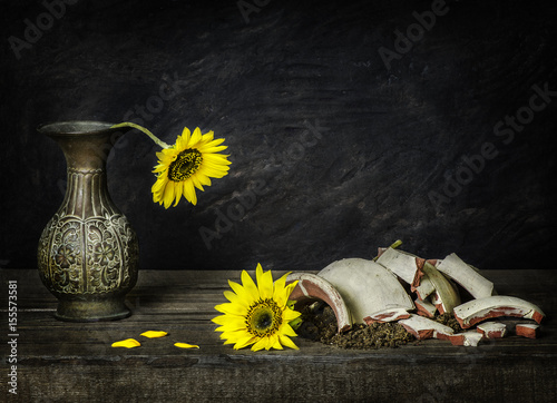 Classic still life with sunflowers placed on rustic wooden background.Brokenness concept photo