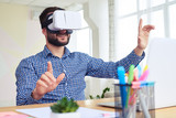 Dark haired male in virtual reality goggles while sitting at table