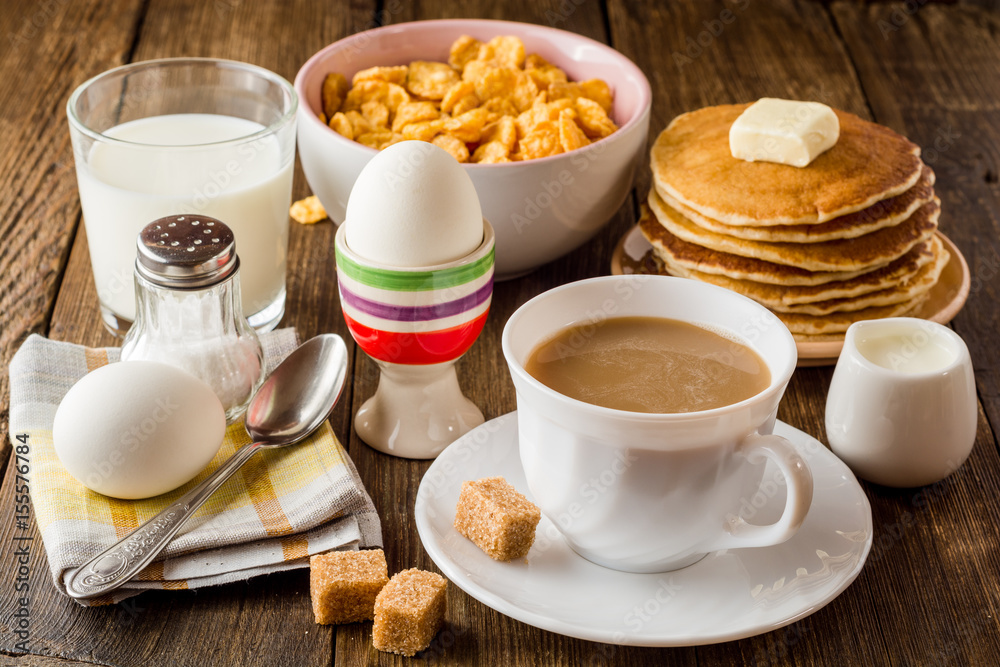 Breakfast table with coffee, boiled eggs, pancakes, cornflakes and milk. Breakfast table with coffee, boiled eggs, pancakes, cornflakes and milk.