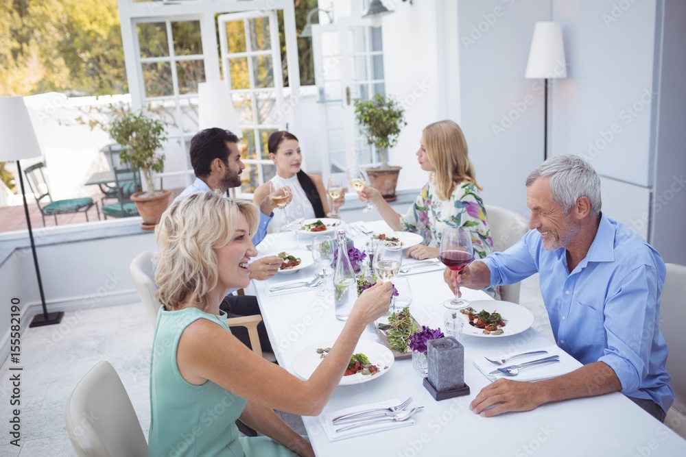 Obraz premium Group of friends toasting glasses of wine during meal