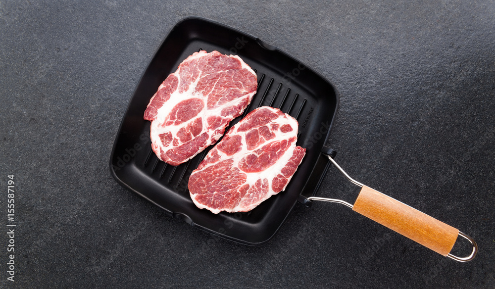 raw steak in a frying pan for the grill on stone background