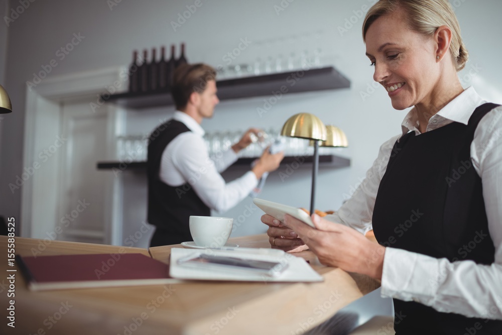 Smiling waitress using digital tablet at counter Smiling waitress using digital tablet at counter