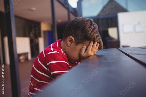 Side view of tired boy leaning on table