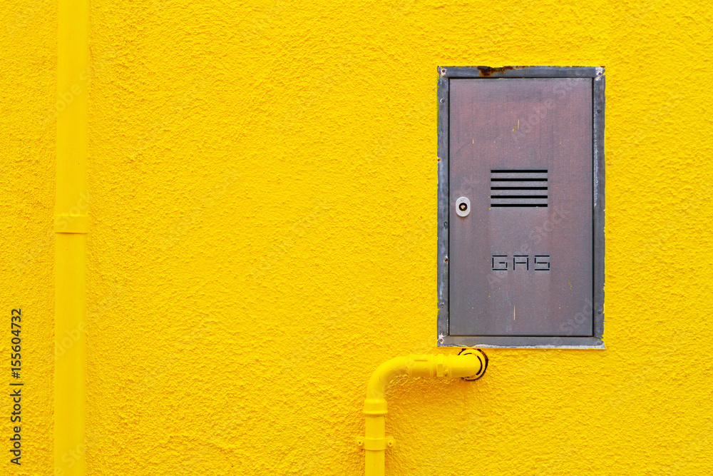 Gas pipe and a technical hatchway in a bright yellow plaster wall Gas pipe and a technical hatchway in a bright yellow plaster wall