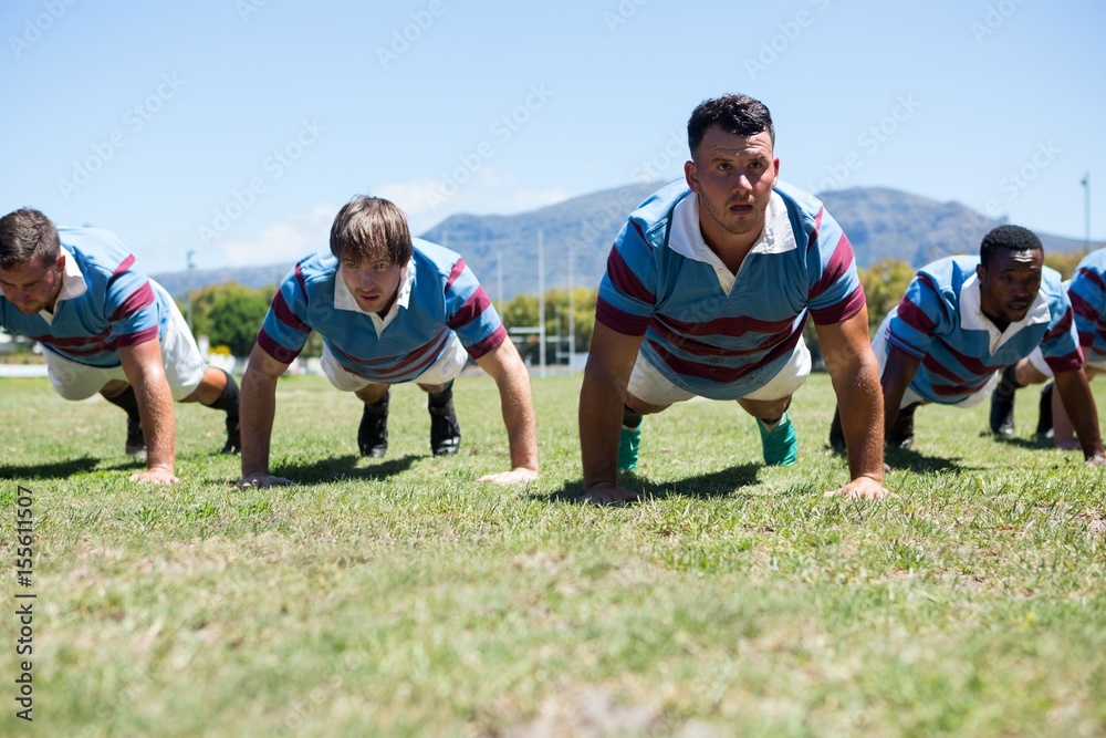 Rugby players doing push up on field Rugby players doing push up on field