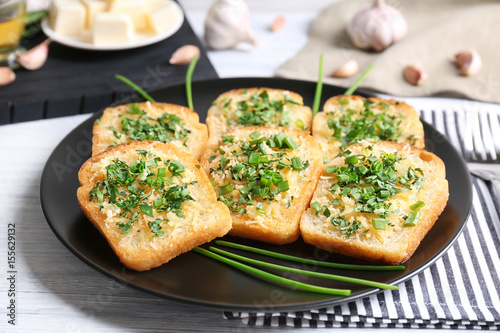 Tasty bread slices with garlic, cheese and herbs on plate