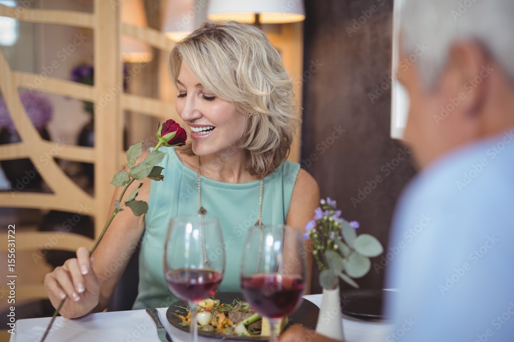 Mature woman smelling a rose flower StockFoto Adobe Stock