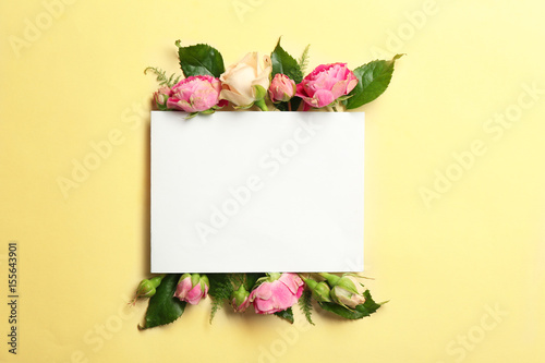 Beautiful flowers and green leaves as floral frame and paper card on color background